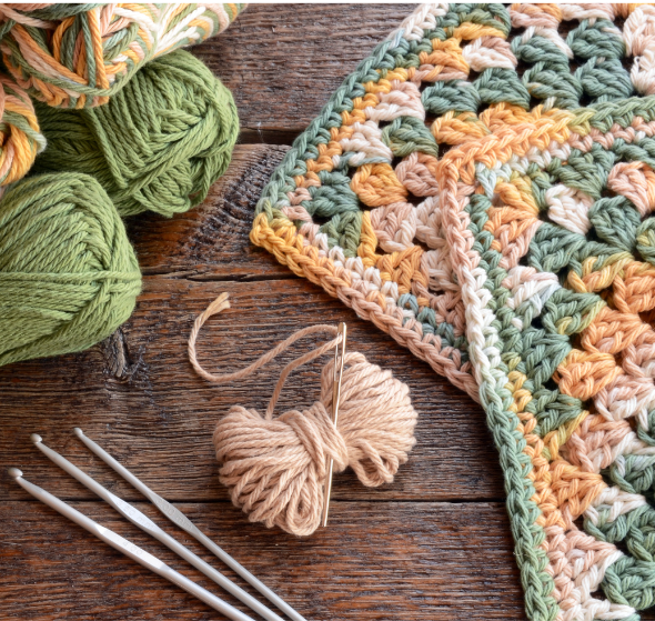 Crochet hook, yarn, crocheted squares